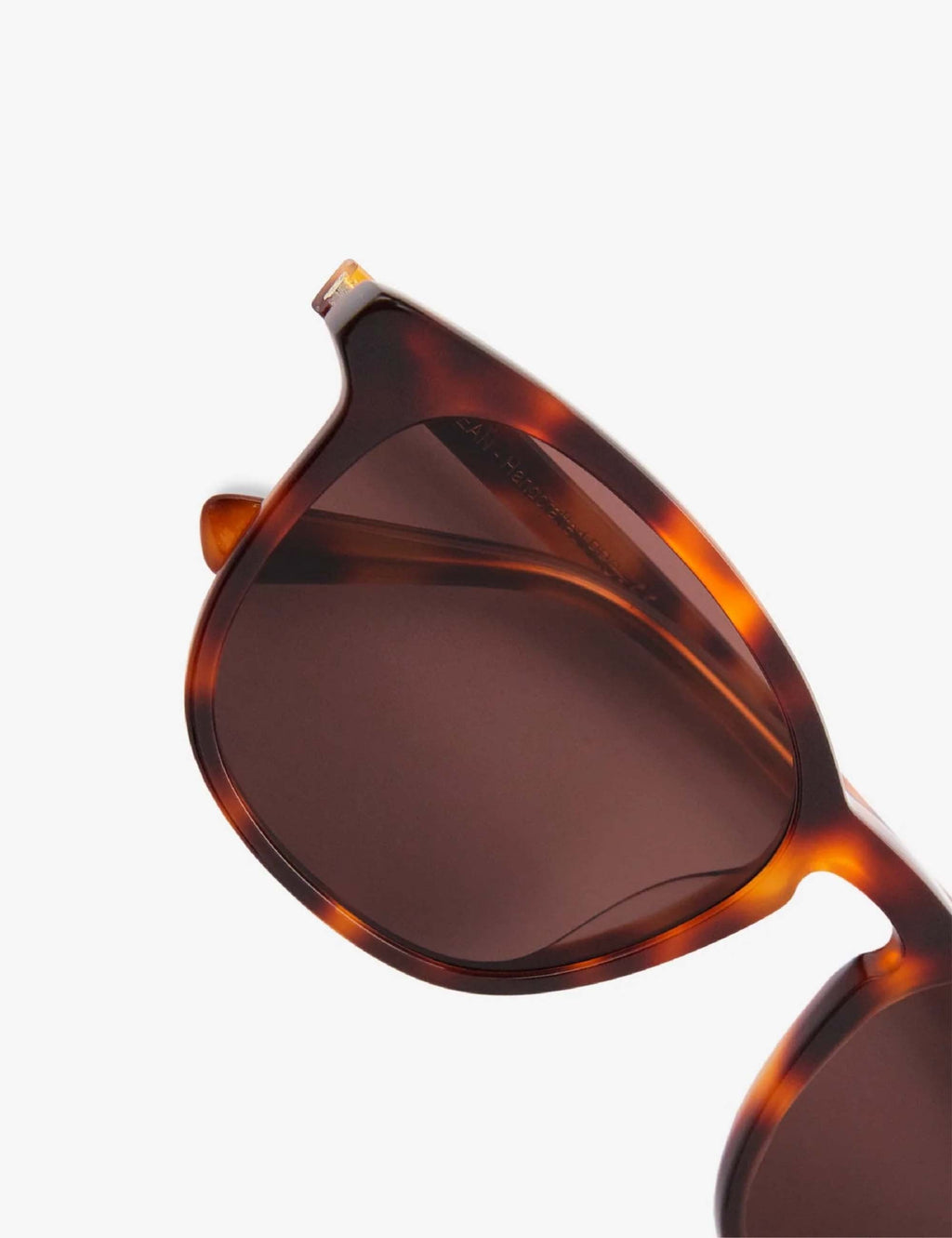 Close-up of brown-tinted lens and tortoise-brown temple on sunglasses