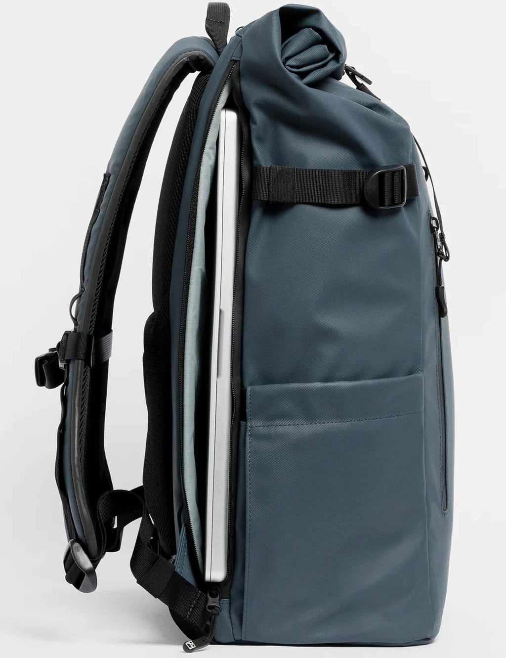 Blue roll-top backpack side view with rolled top, webbing strap, and zip pocket.