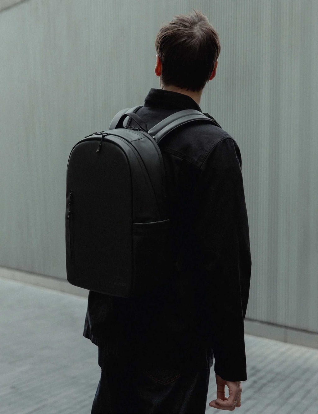 All-black backpack worn on back, side view with adjustable shoulder straps