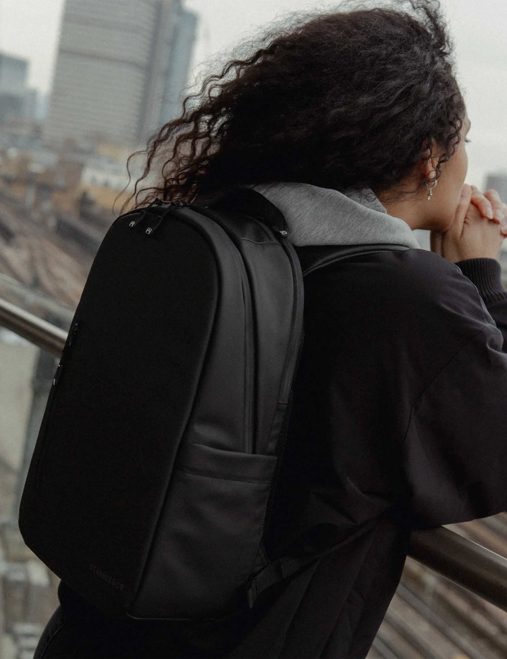 All-black backpack worn on back with coat collar visible