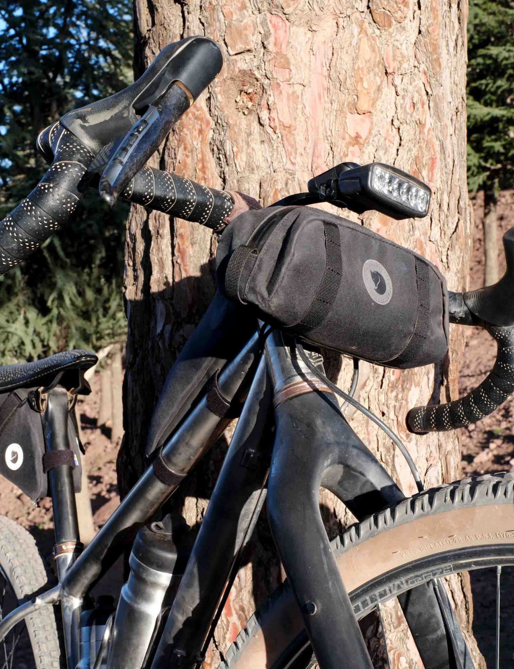 Black handlebar pocket bag close-up with round logo patch and zippered front.