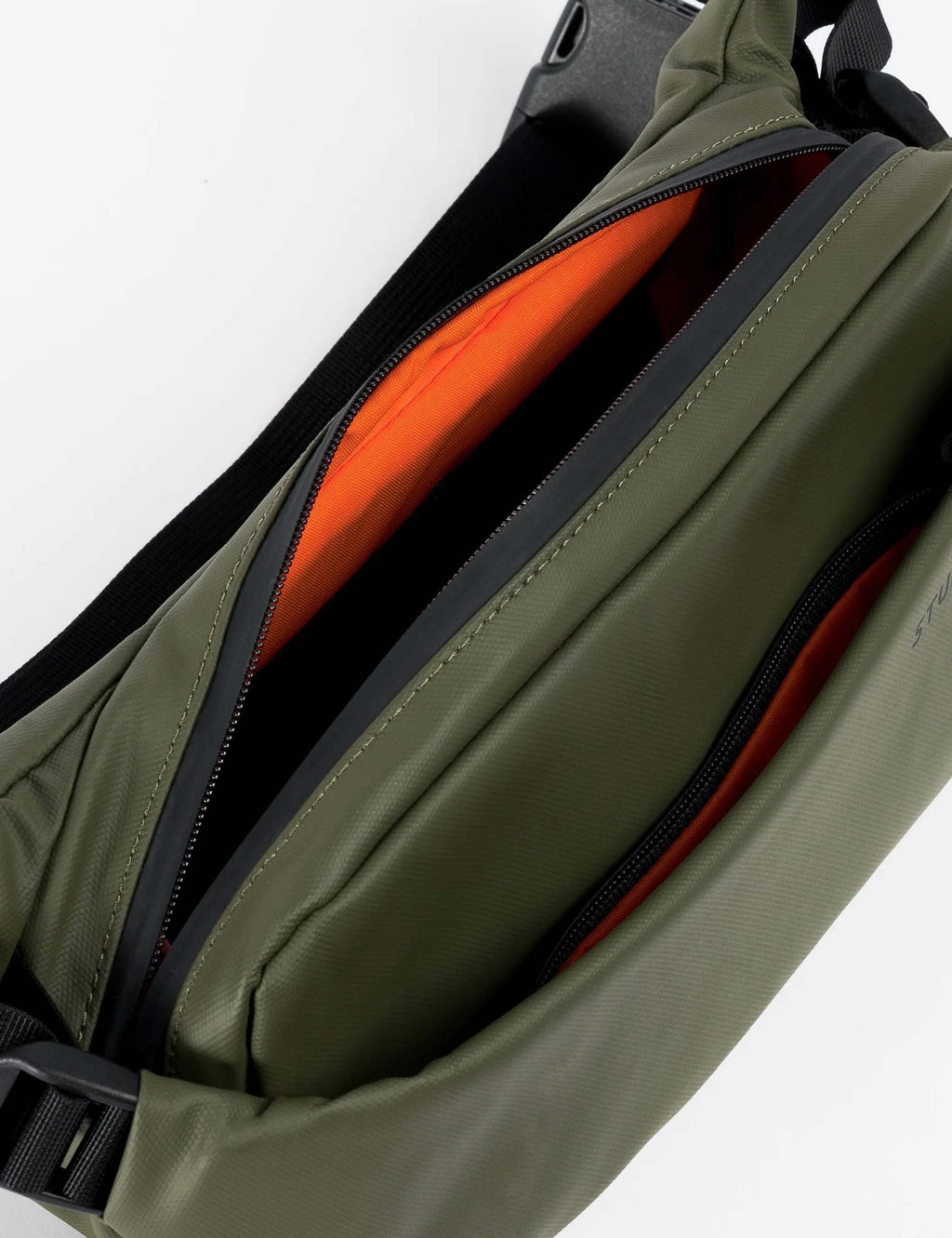 Crossbody bag interior with orange lining and zipper compartments in olive green