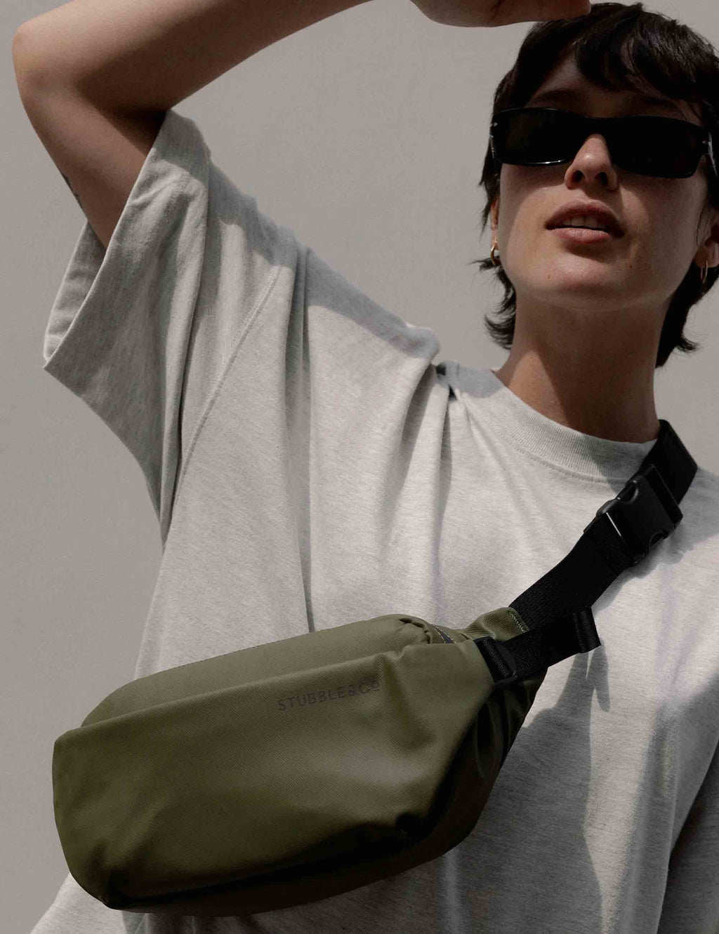 Olive green crossbody bag with black strap, worn across the chest