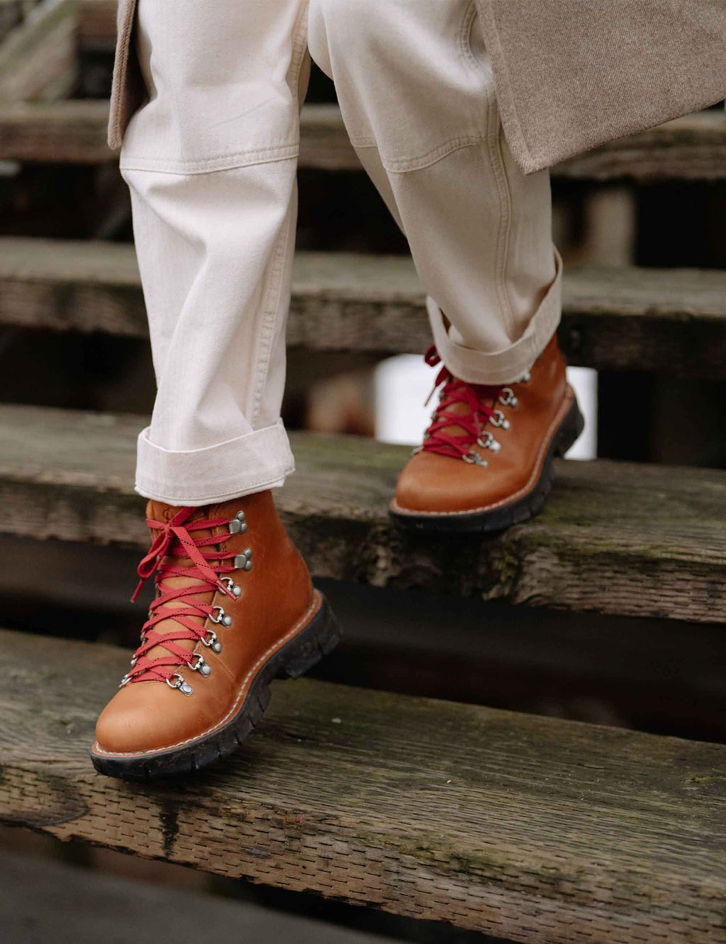 Tan hiking boots with red laces and white pants