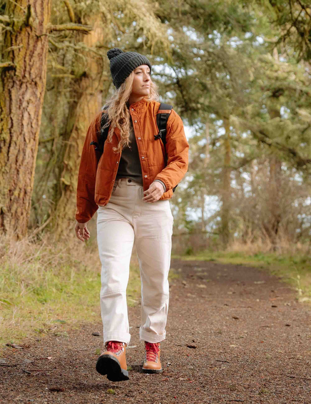 Tan hiking boots with red laces worn by woman on forest path