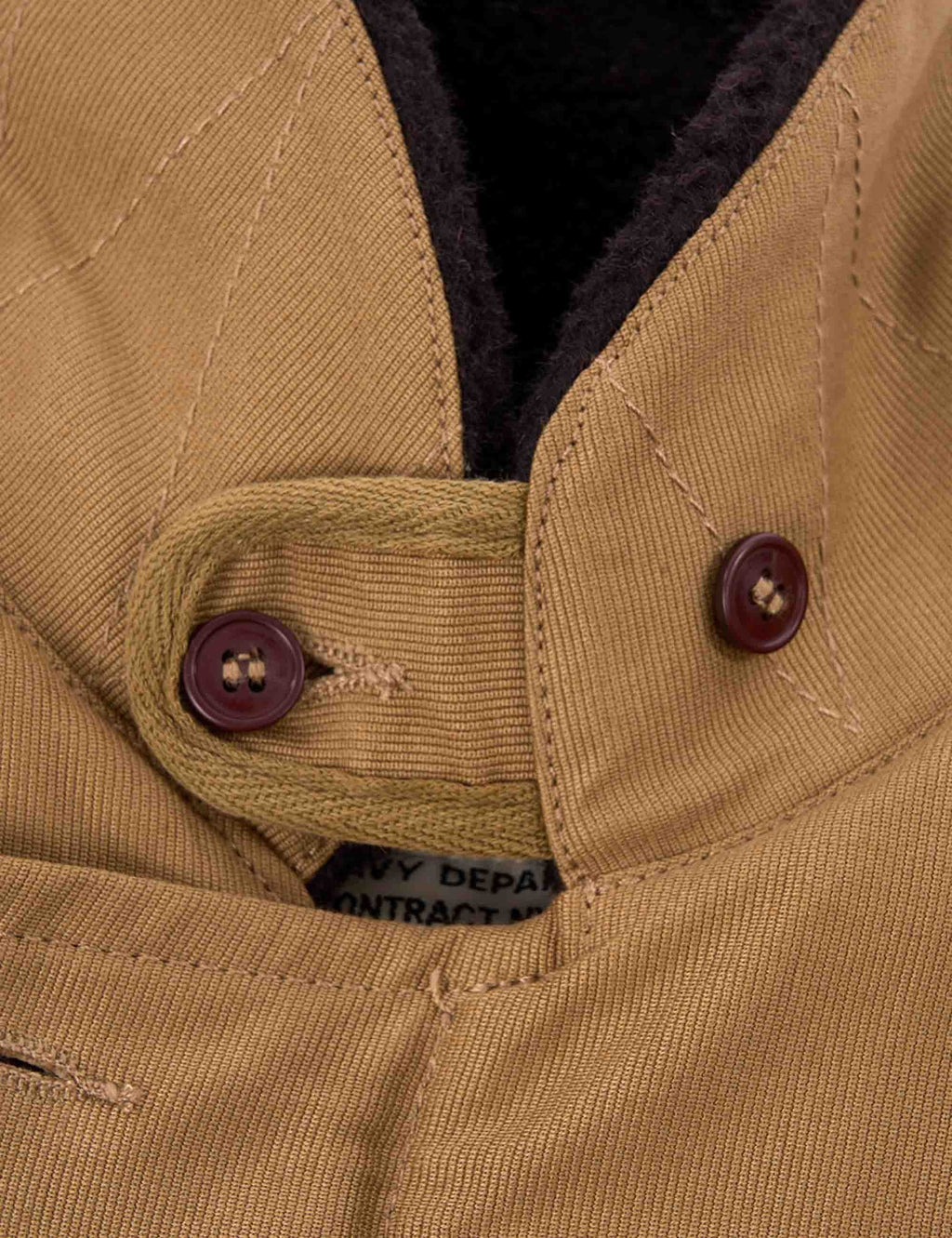 Tan deck jacket shoulder with maroon button and dark inner lining detail