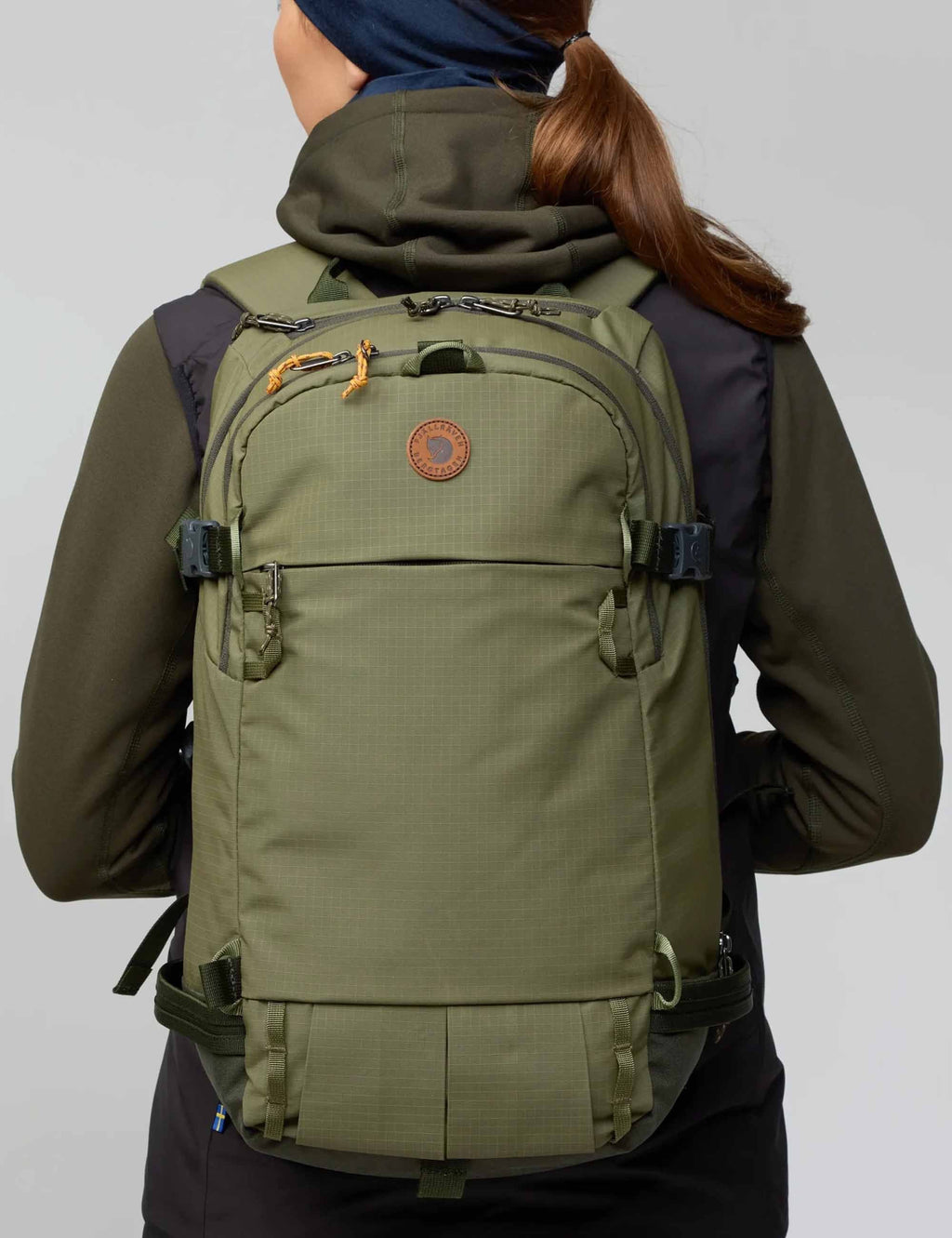 Touring backpack in laurel green, worn on back with shoulder and chest straps