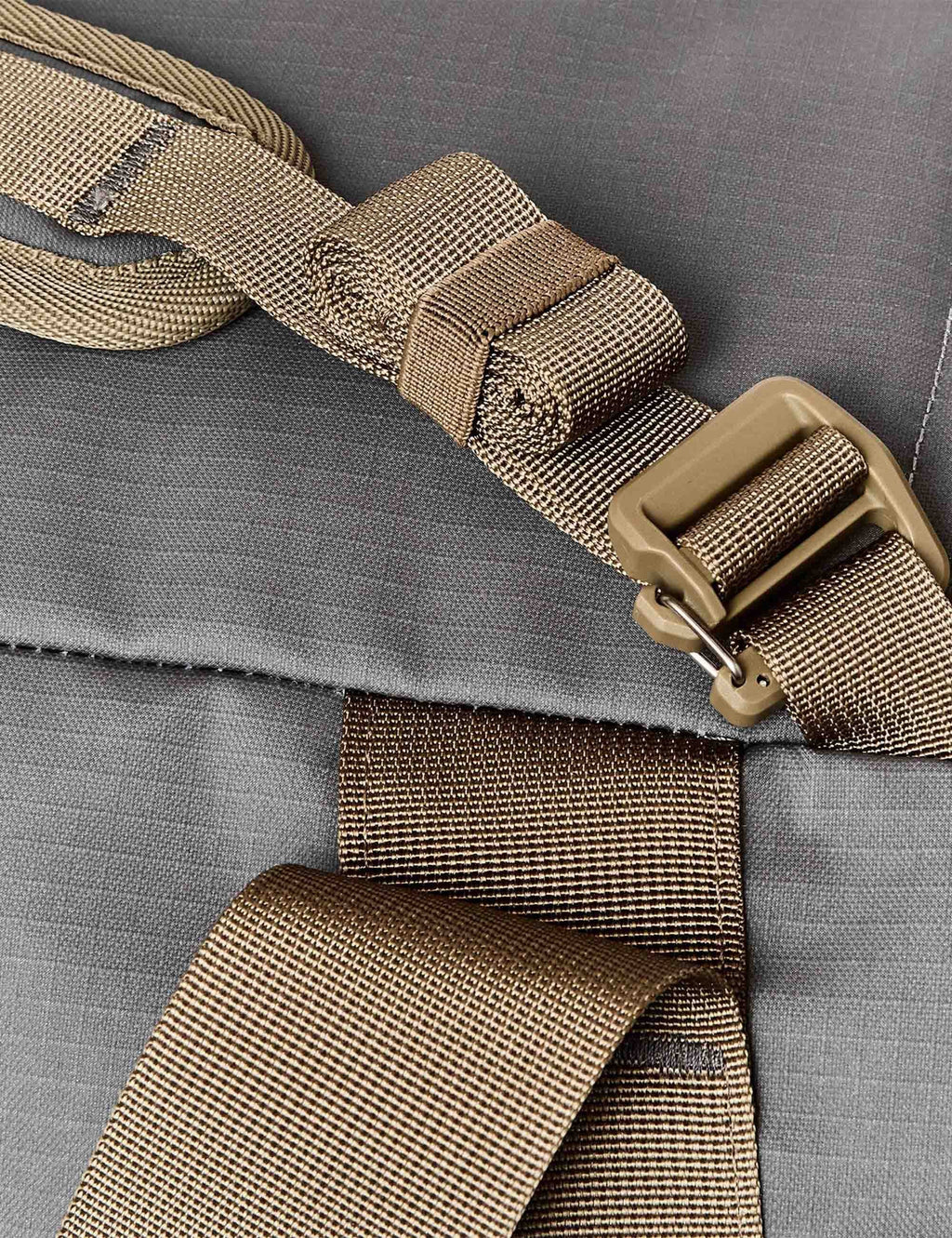 DuFFel bag strap with tan webbing buckle and metal adjuster on gray fabric