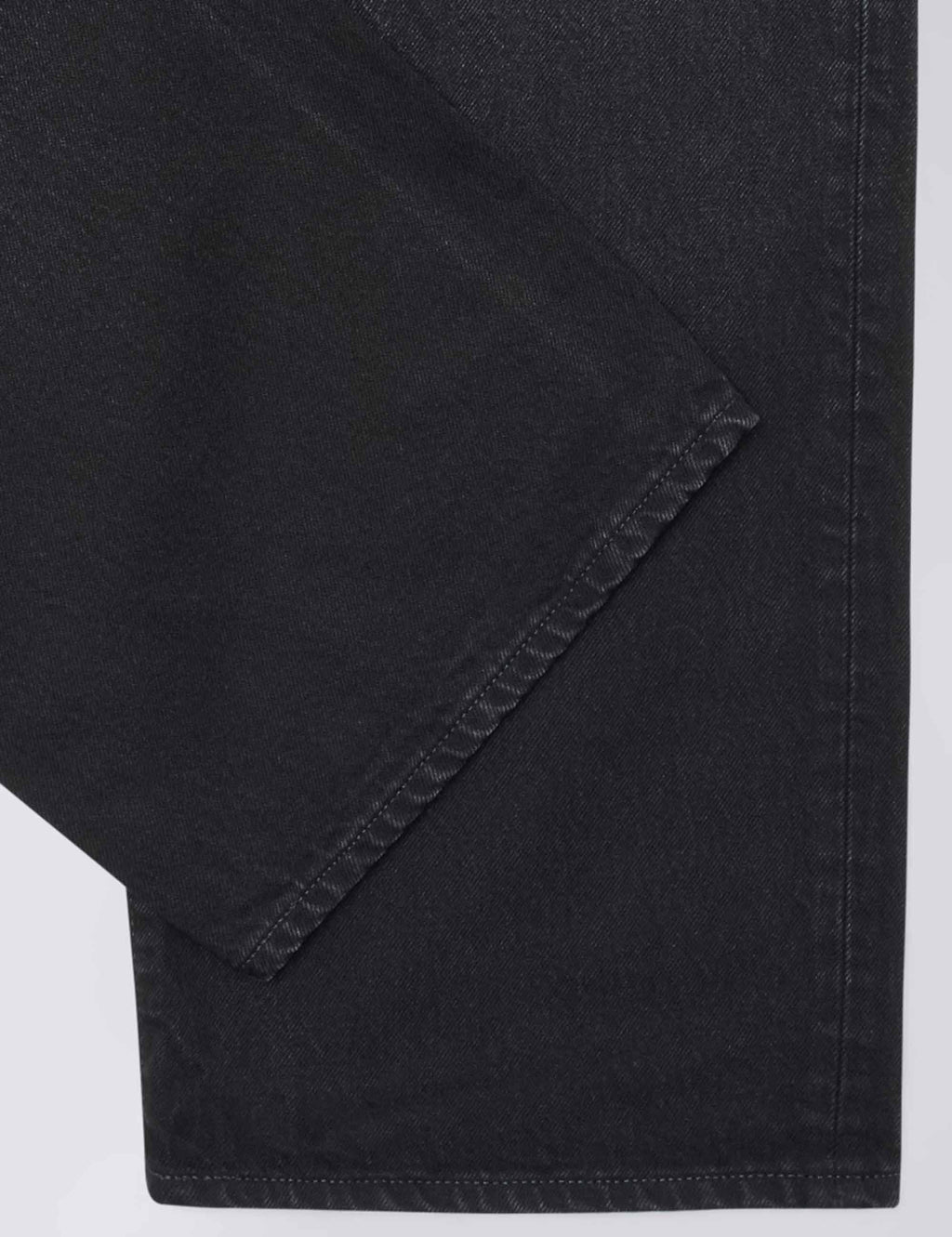 Dark black denim pant leg hem with stitched seam detail and slight worn-in creases