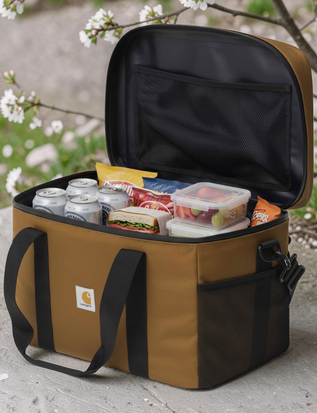 Brown cooler bag with black interior, filled with food and drinks, outdoors.