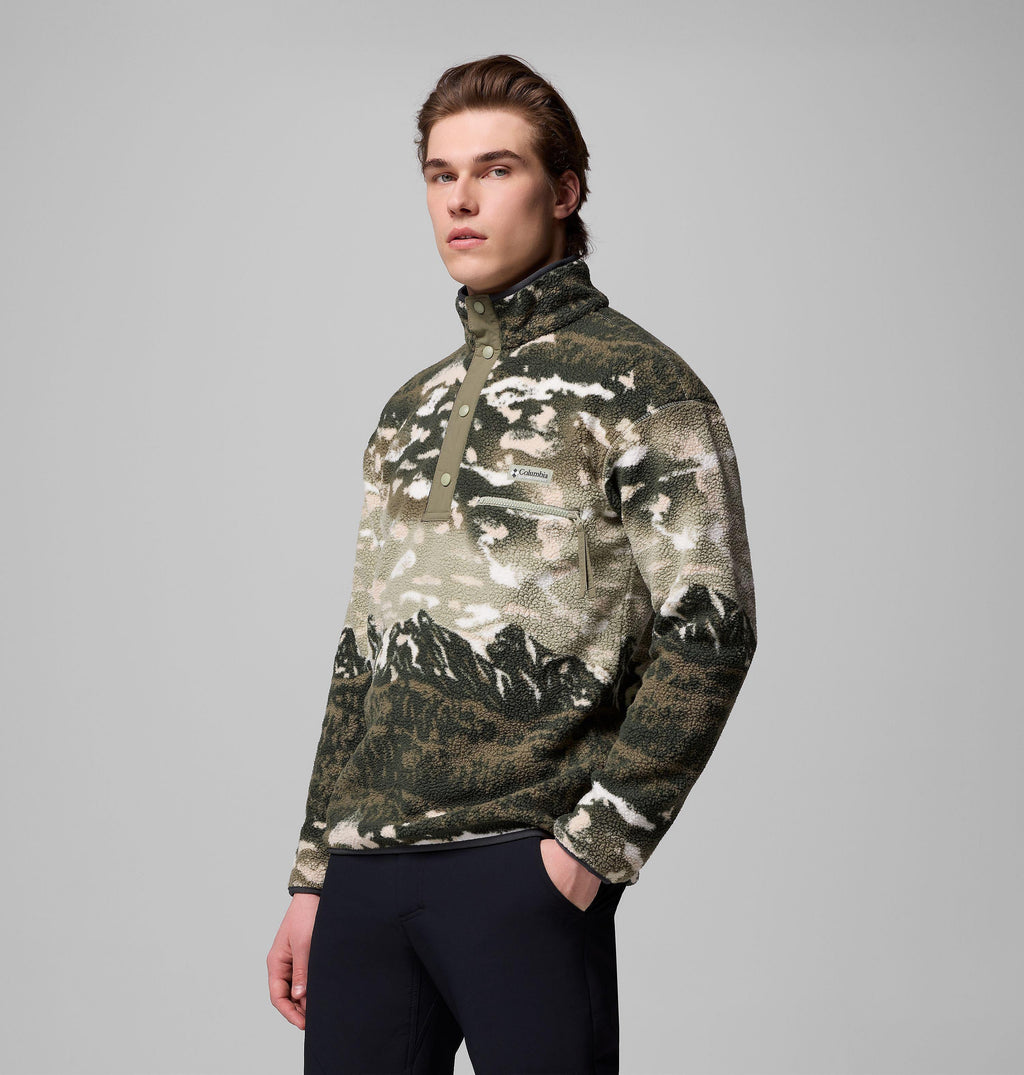 Men's khaki landscape-print fleece pullover, angled view, hand in kangaroo pocket, zipped chest pocket