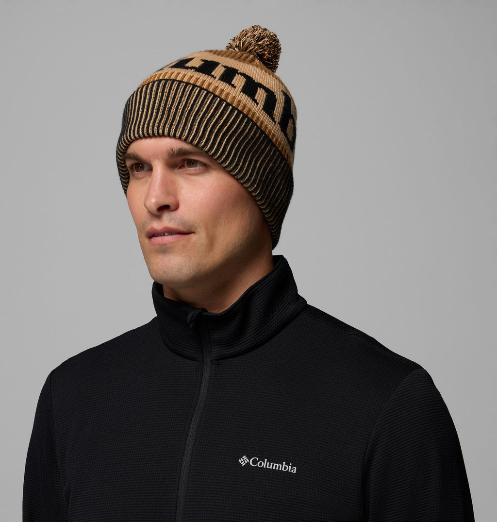 Camel brown knit beanie with black stripe band, logo patch, and pom-pom