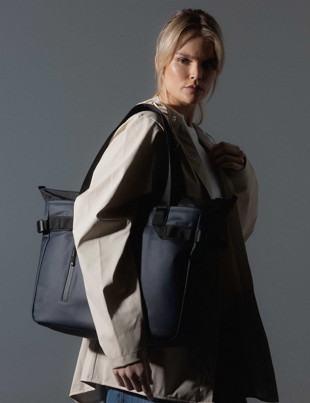 Midnight blue laptop tote bag worn over shoulder with zip front pocket