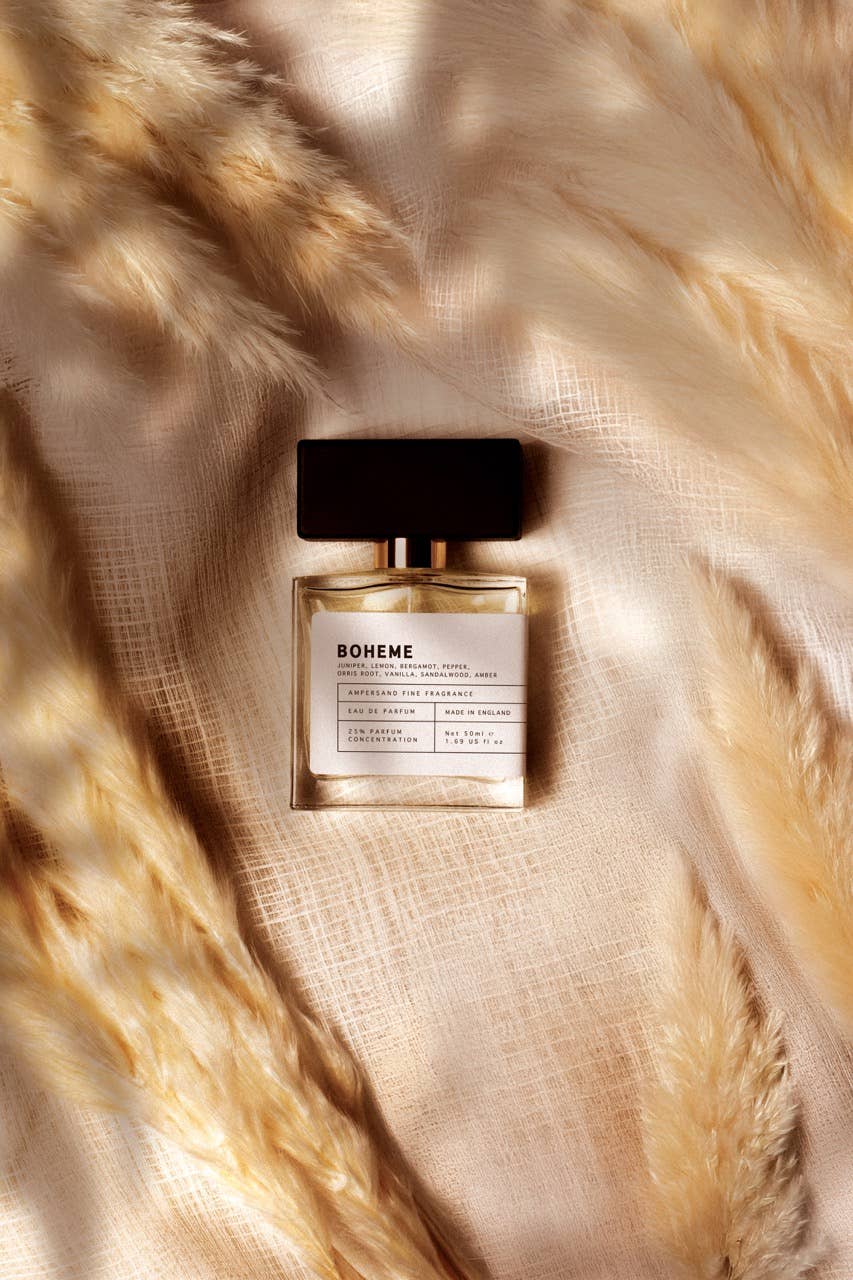 Unisex EDP perfume bottle with black cap on tan fabric, amber glass and white label