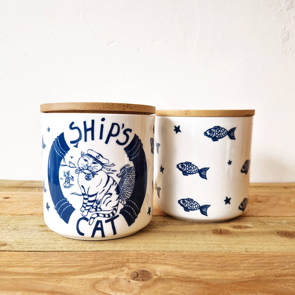 Pair of white ceramic cat treat jars with blue cat and fish prints and bamboo lids