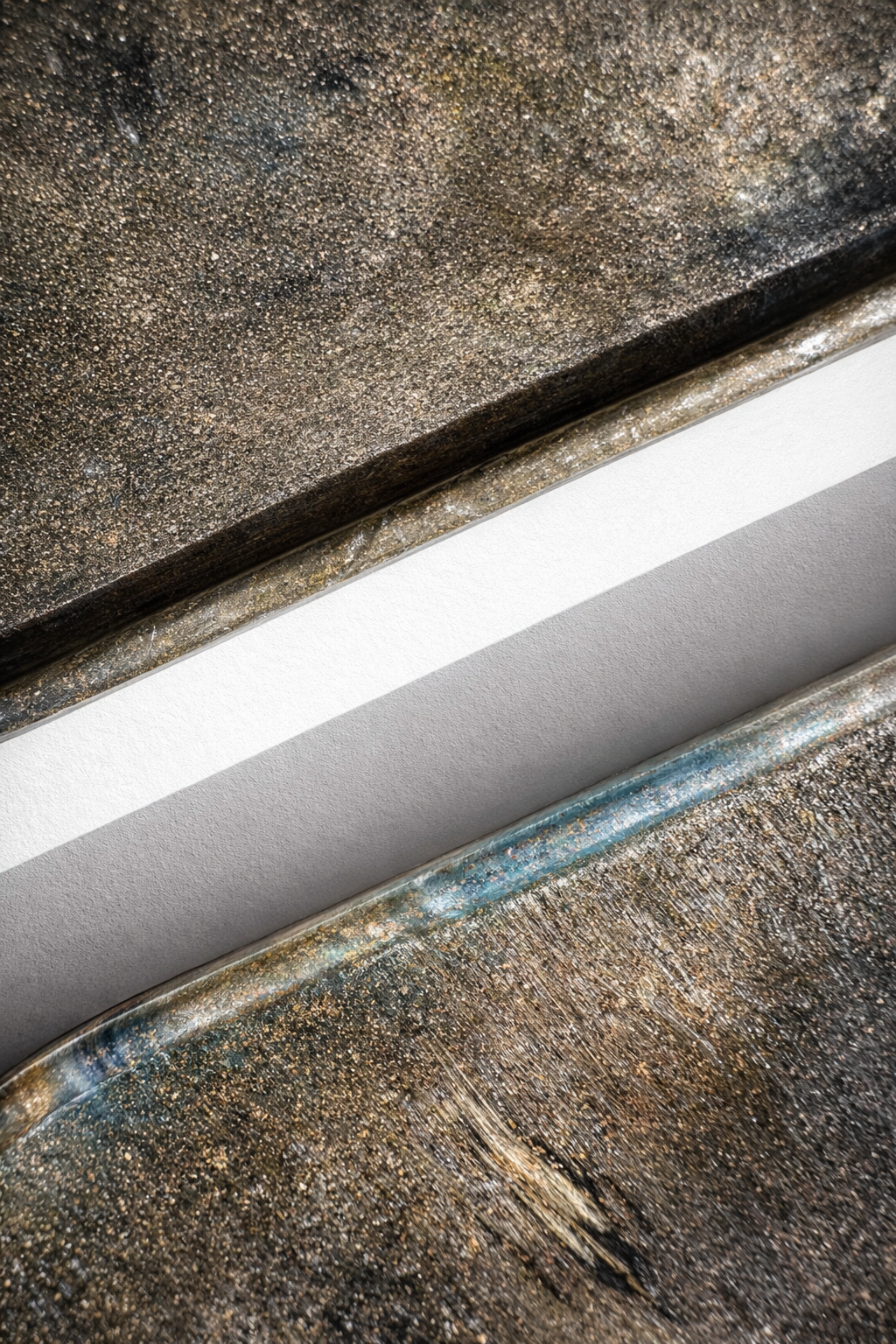 Recycled plastic tray rim detail, speckled bronze with blue streaks and scuffs.