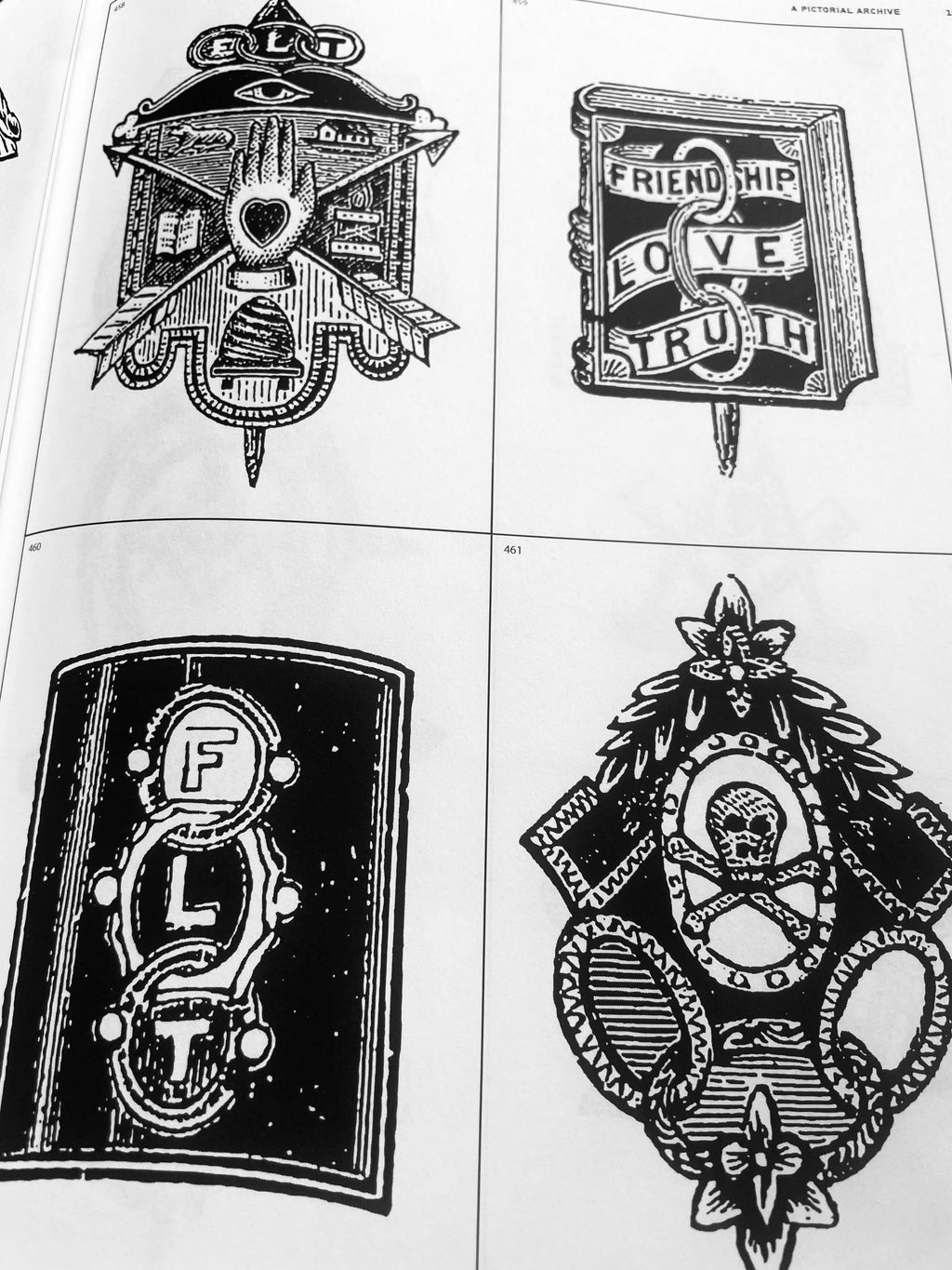 Open book spread with robot-like emblem, lantern sign, heart-in-house motif, and mask