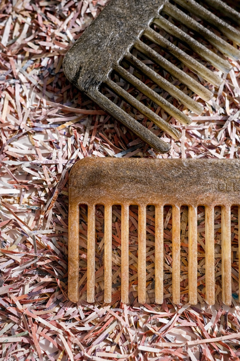Recycled plastic hair comb, tan and dark tones, fine teeth close-up.
