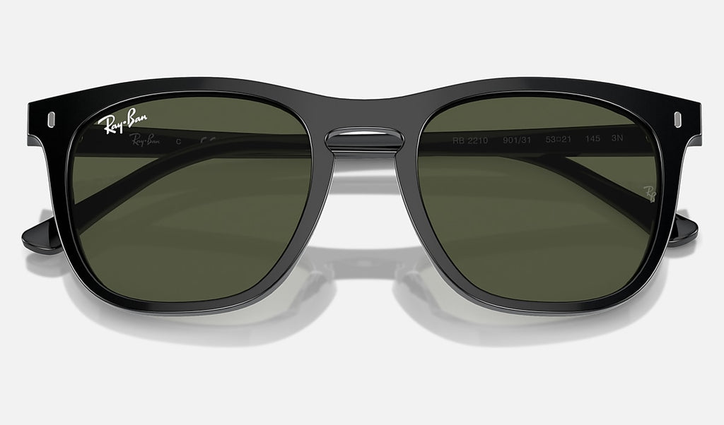 Black sunglasses with green tinted lenses, rounded square frame, temple tips visible, Ray-Ban logo.