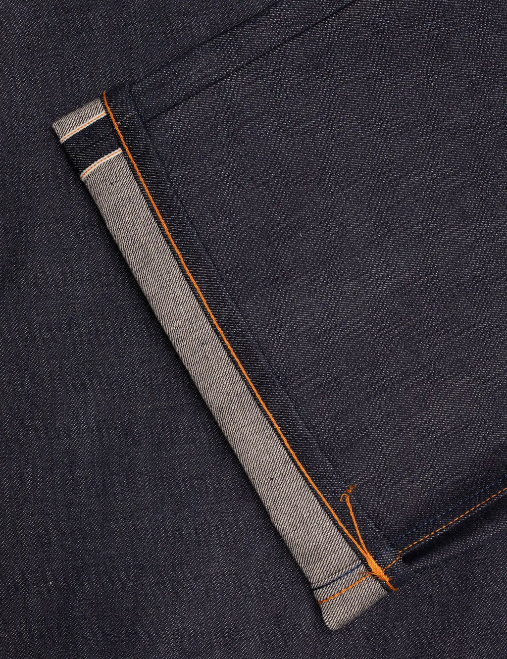 Dark indigo selvedge jeans cuff with orange contrast stitching and beige inner band