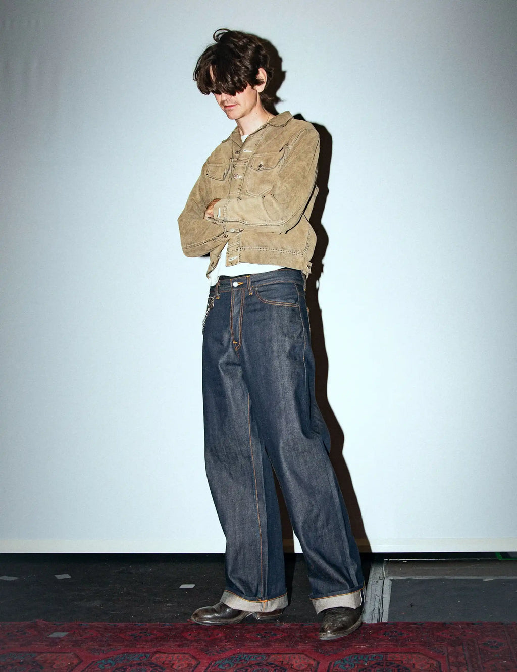 Dark indigo wide-leg jeans with orange-stitched pockets and visible selvedge hem
