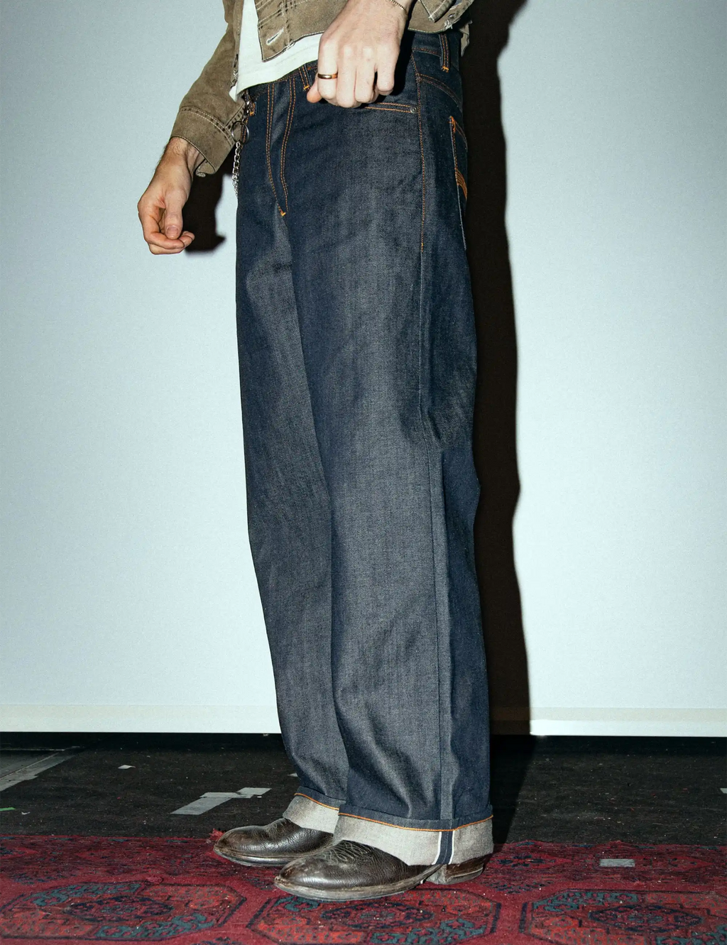 Dark indigo loose-fit jeans with orange topstitching, pocket seams, and selvedge hem