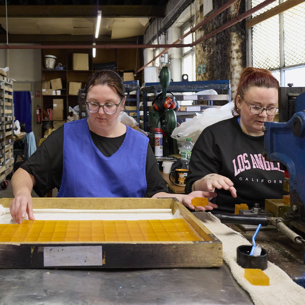 Rectangular yellow soap bar pieces on a workbench, stamped in a grid.