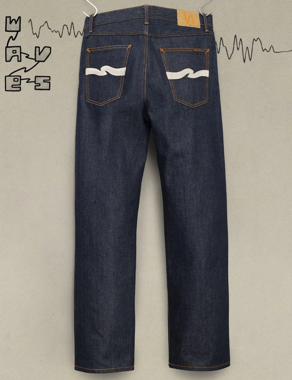 Dark indigo jeans with ecru wave patches on back pockets and orange contrast stitching