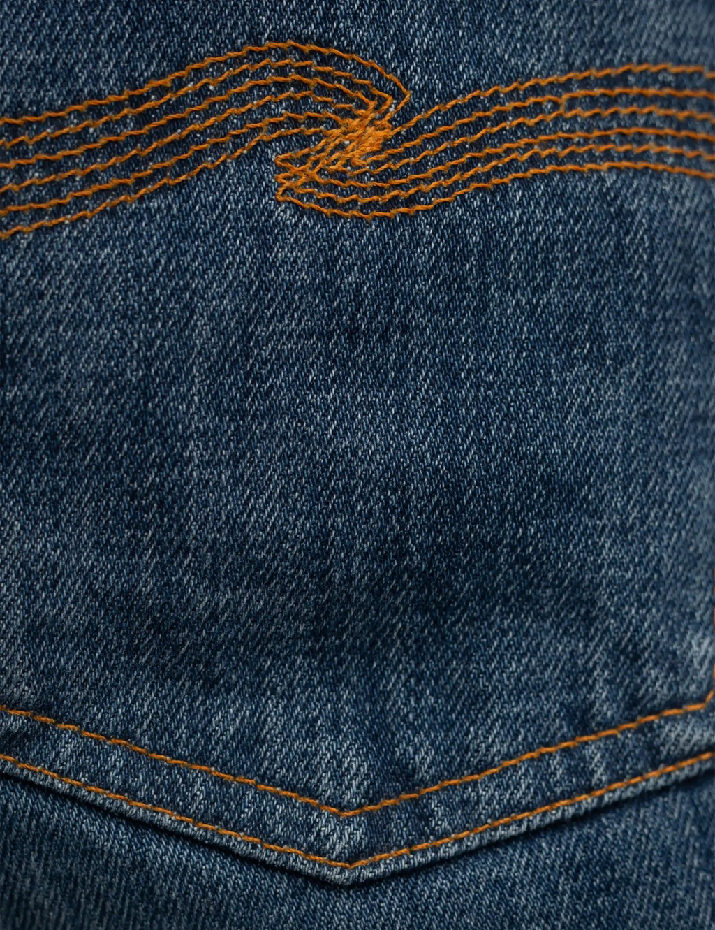 Blue denim jeans with twisted orange topstitching across the yoke and pocket seam