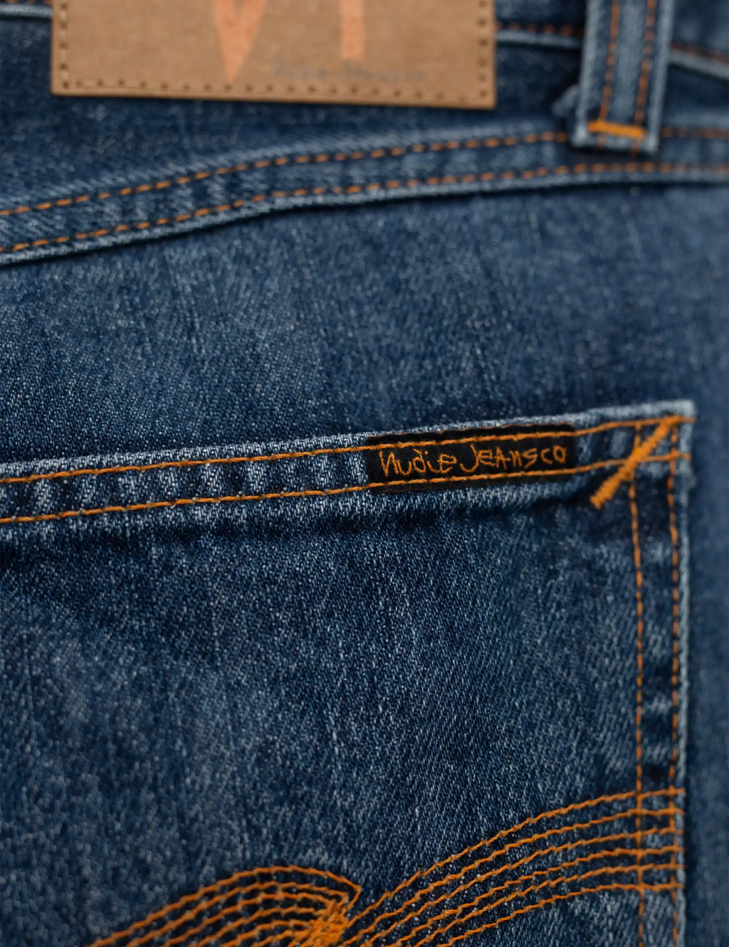 Blue denim jeans waistband patch with twisted orange stitching detail