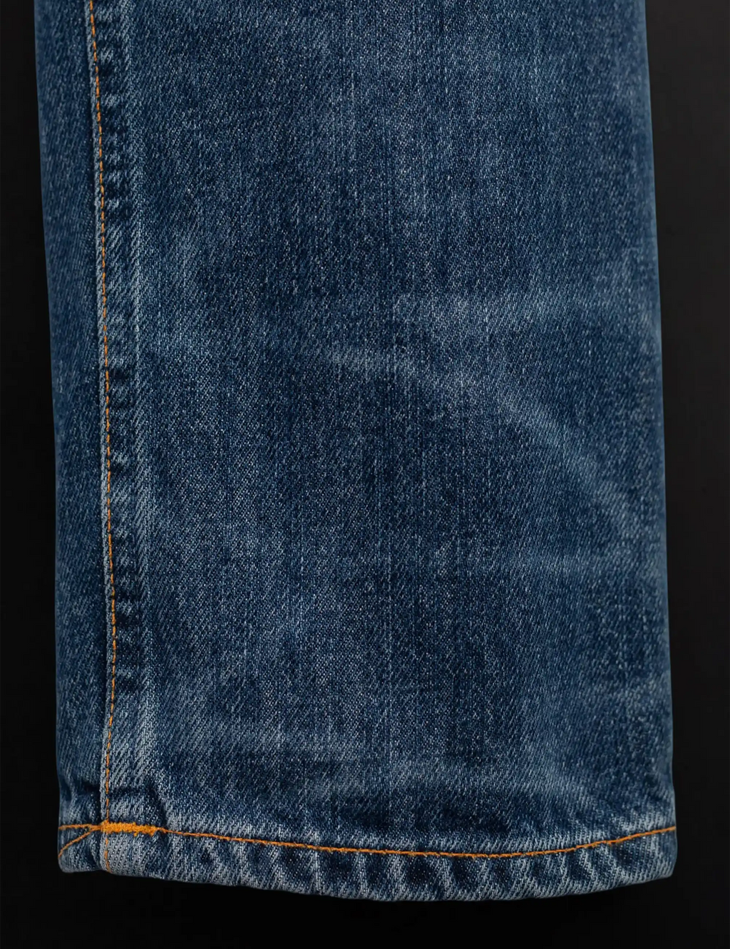 Blue denim jeans hem with orange contrast edge stitching