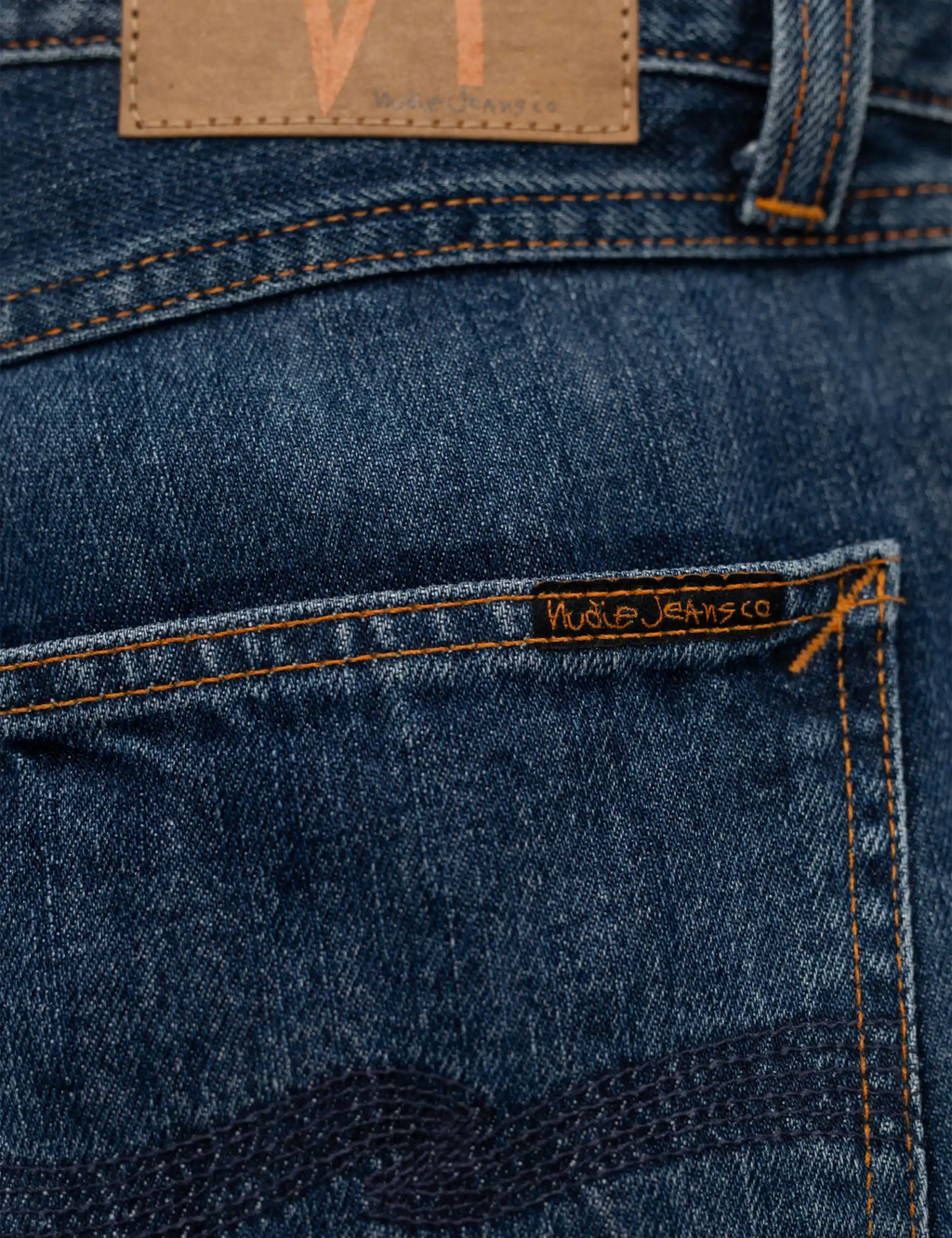 Blue jeans waistband with tan leather patch and orange contrast stitching