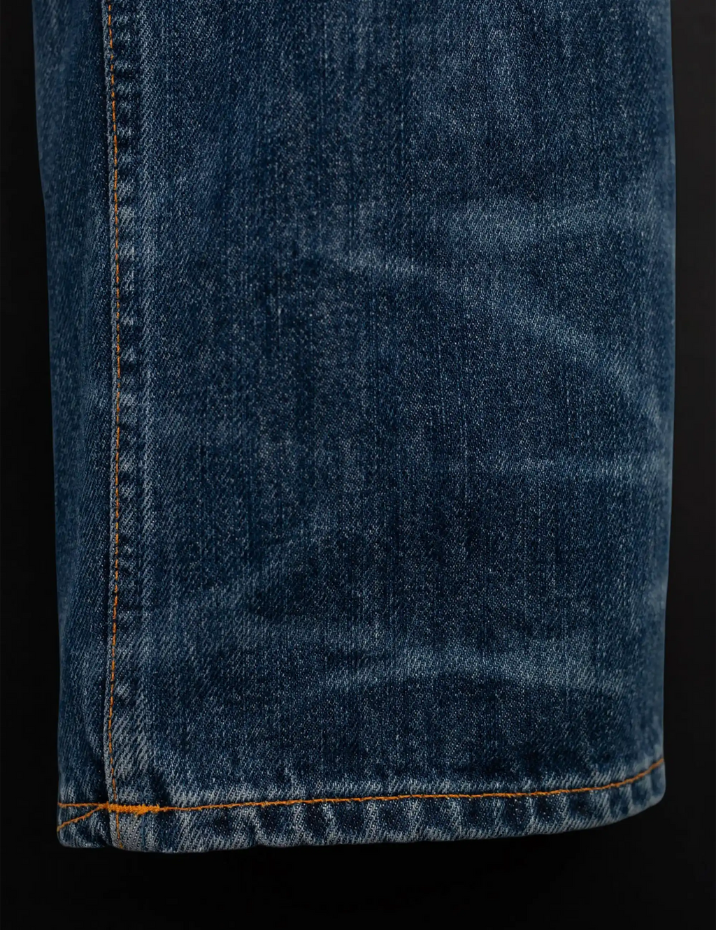 Blue jeans hem with visible cuff stitching and slight fray at the bottom