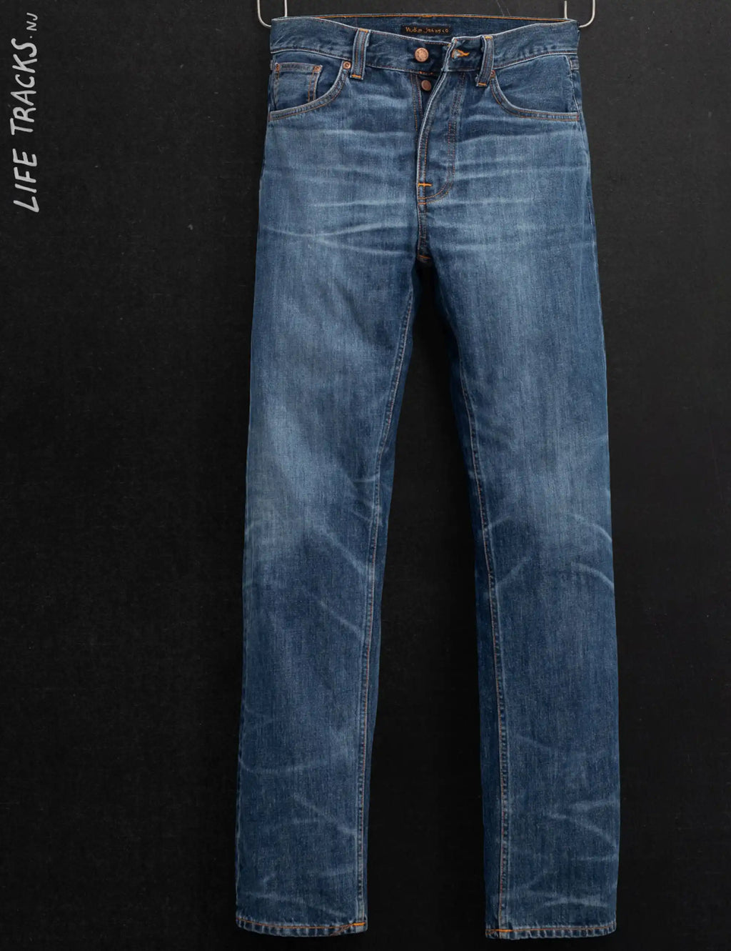 Light blue jeans laid flat with front pockets and orange contrast topstitching