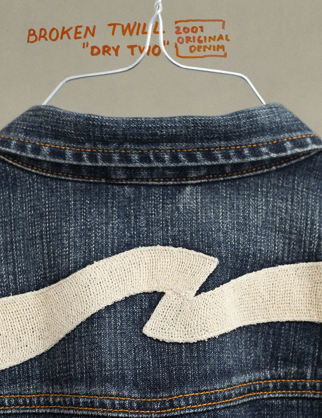 Dark blue denim jacket back yoke with distressed cream wave graphic and contrast stitching