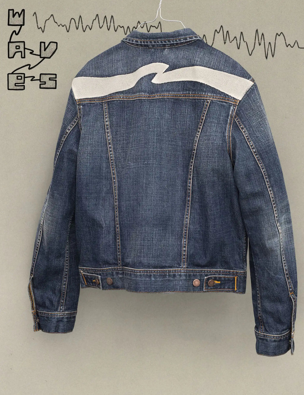 Dark blue denim jacket back with cream wave graphic across the shoulders and back seams