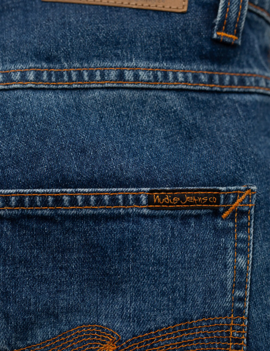 Blue denim jeans with orange stitched seams and a woven back patch label