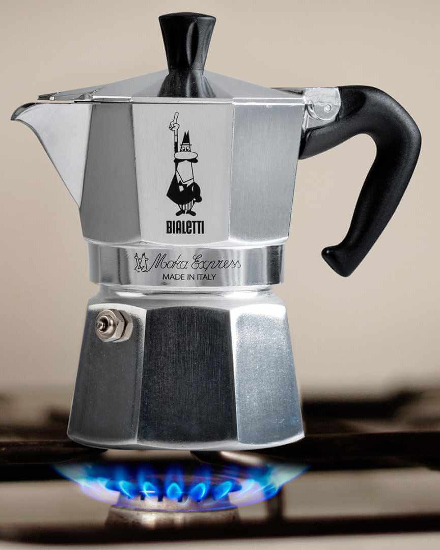 Bialetti Moka Express coffee maker on a stovetop with a beige background