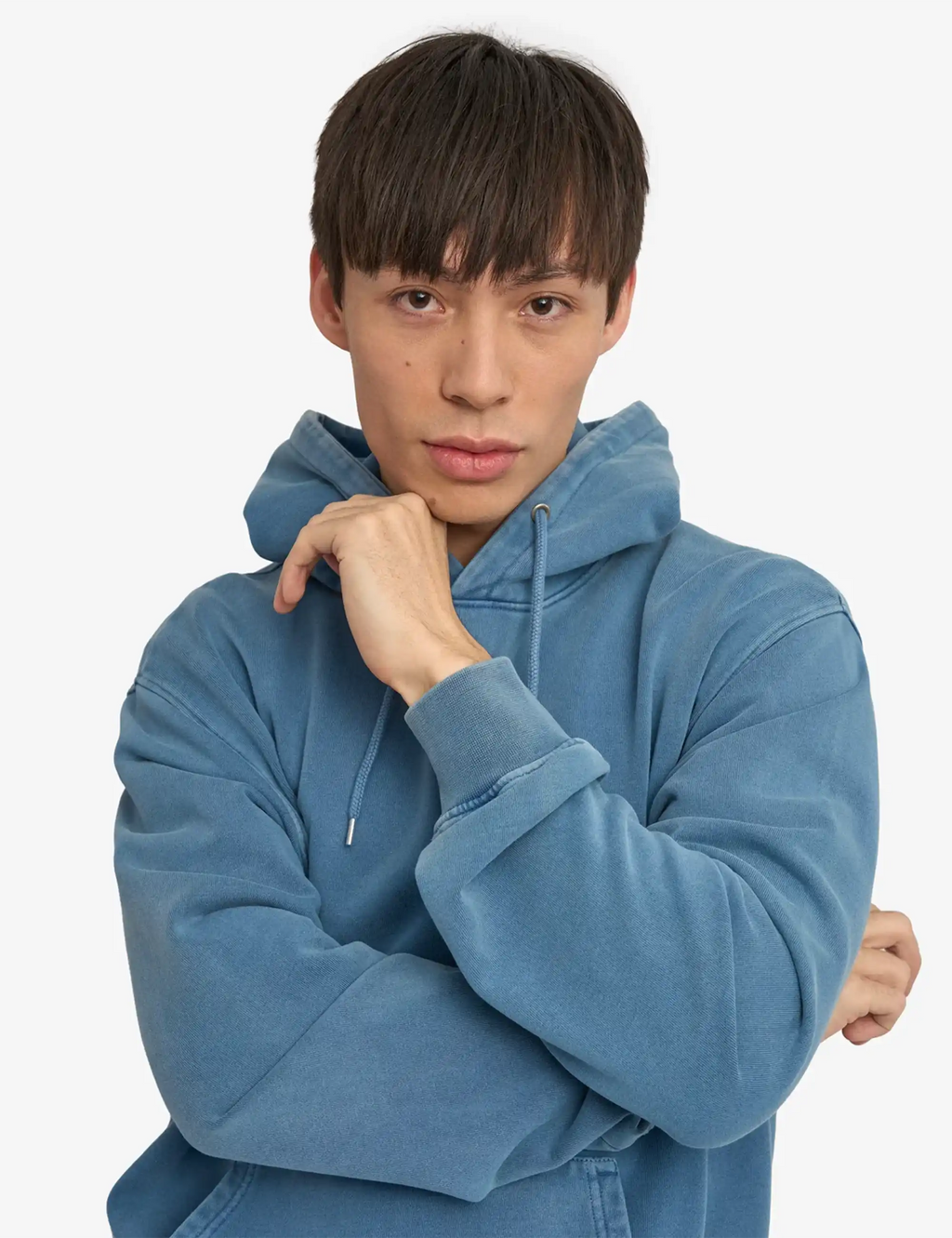 Faded indigo hoodie close-up: drawstring hood and kangaroo pocket detail.