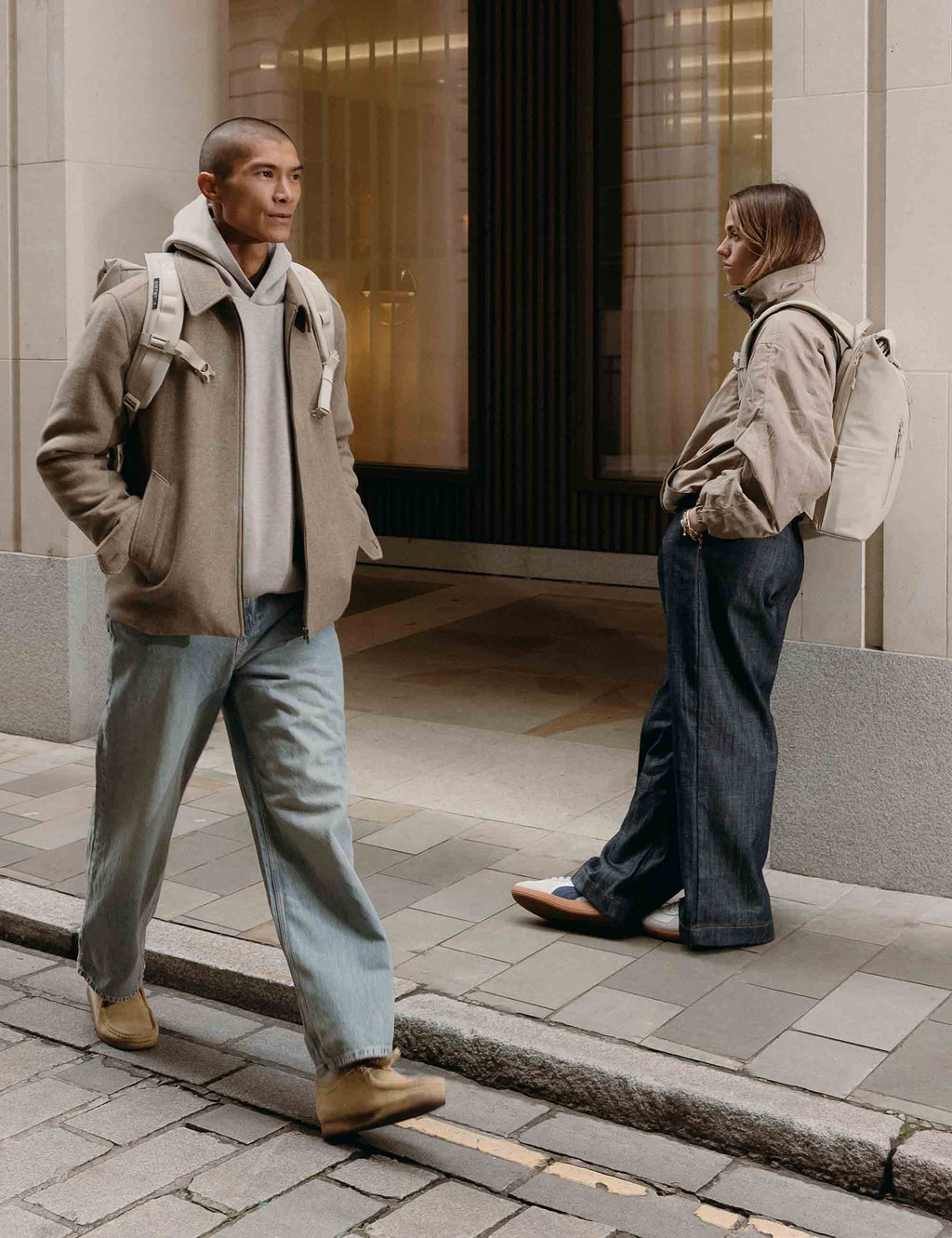Tonal sand roll-top backpack worn, with adjustable shoulder straps and top roll closure.