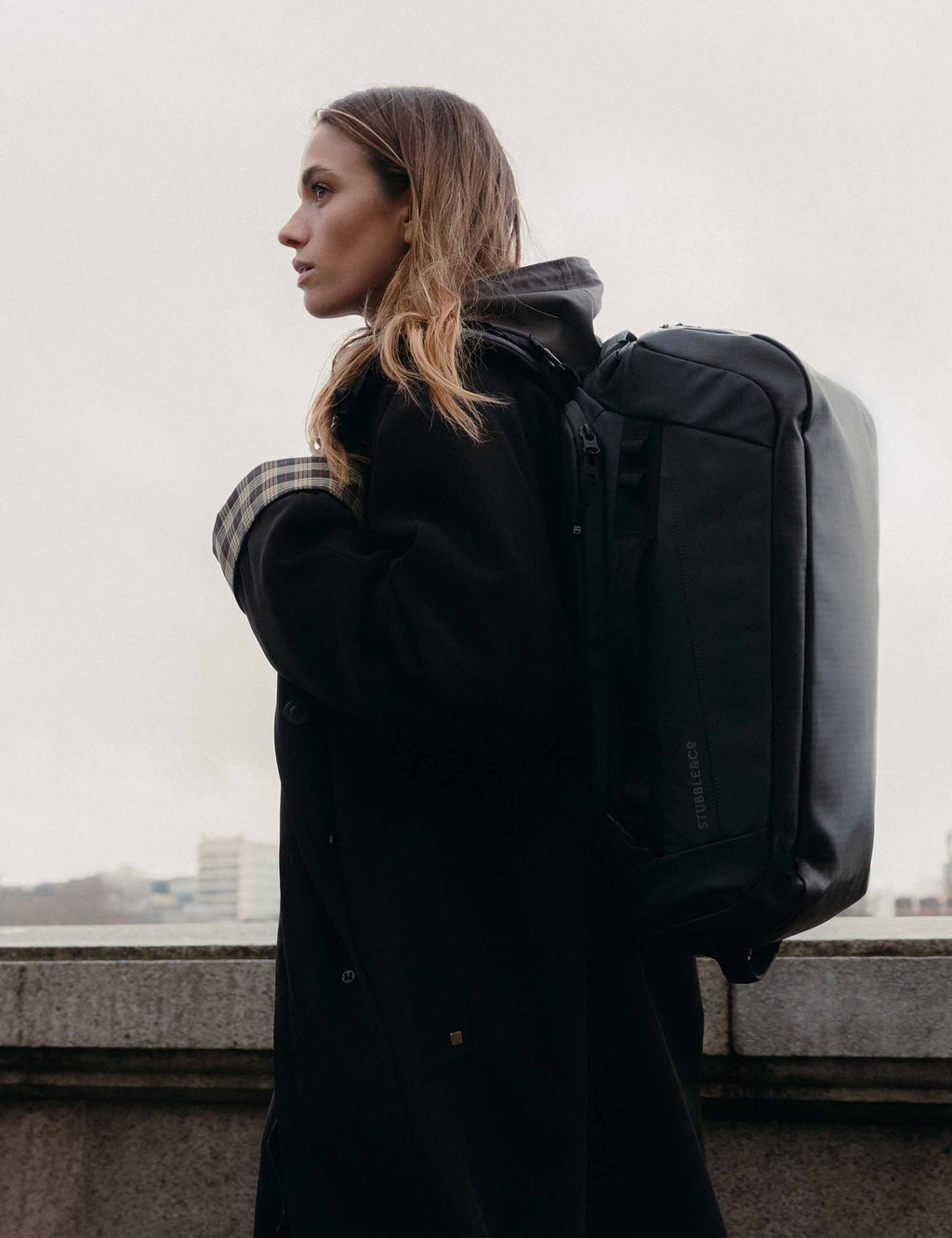 Dark duffel backpack with front zip, side handle, and padded back panel