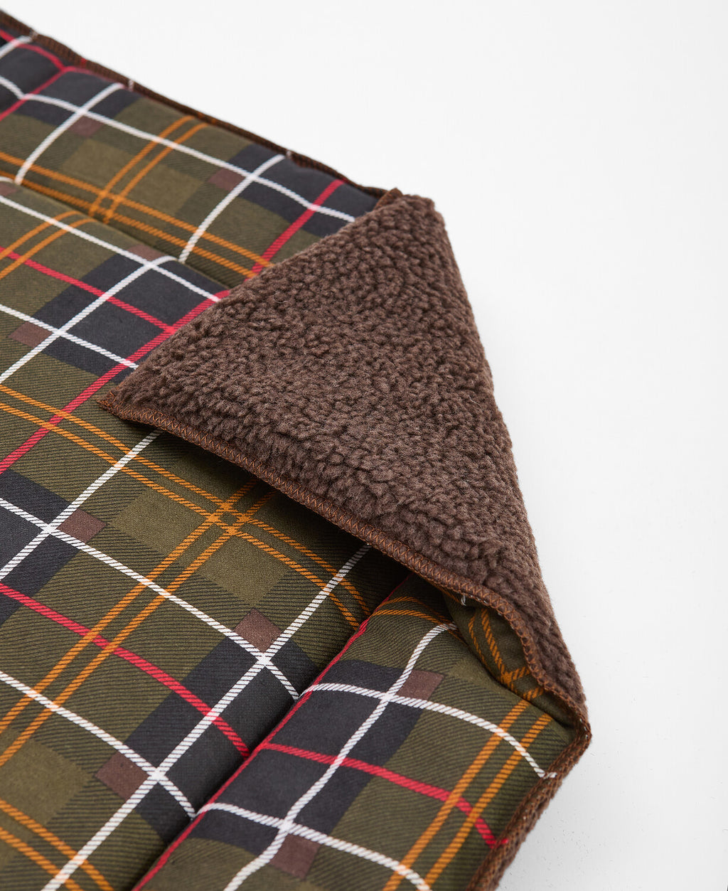 Tartan dog mat corner with brown fuzzy border and stitched edge