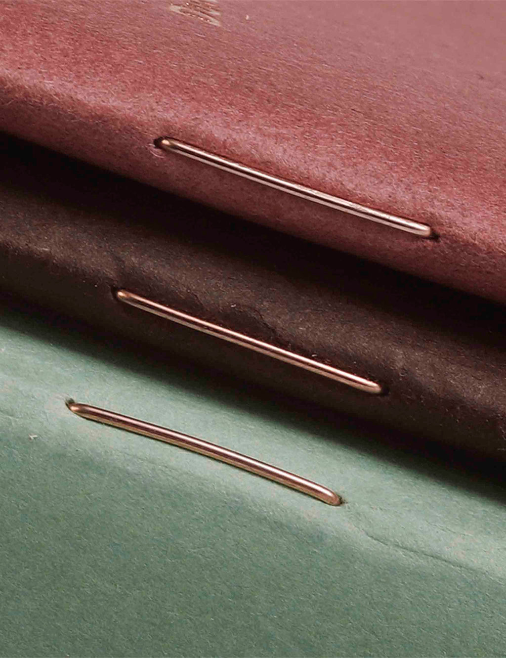 Quarterly memo book spine with metallic binder rings on maroon and mint covers