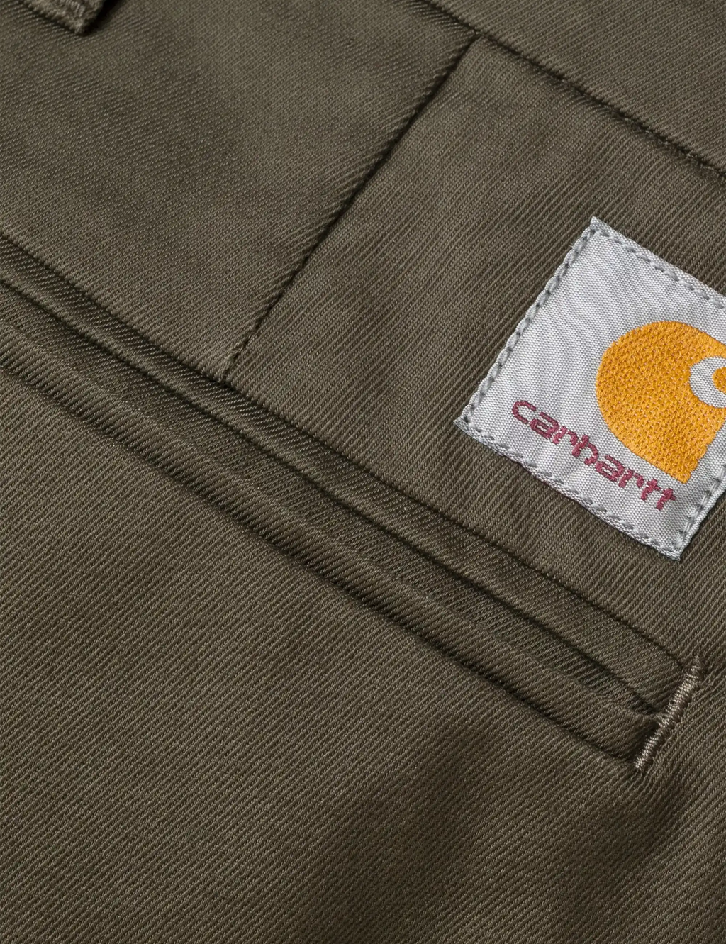 Carhartt brand label on dark cypress pants fabric near the waistband seam