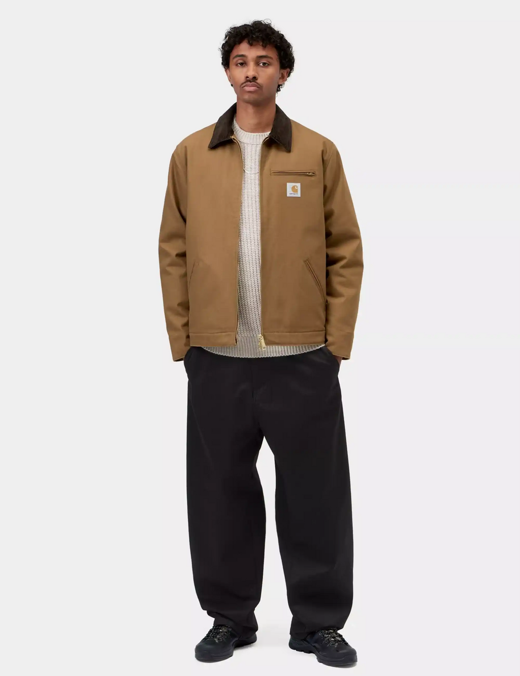 Men's tan winter jacket with dark collar, full-zip front, chest pocket over knit