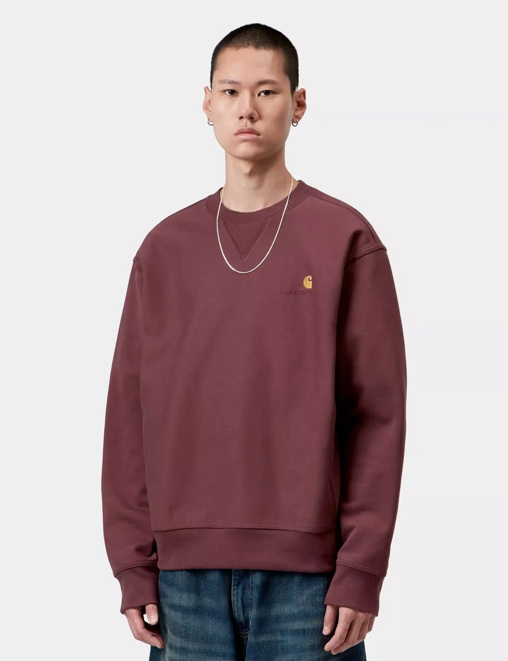 Maroon crewneck sweatshirt with small yellow chest logo, long sleeves and ribbed hem