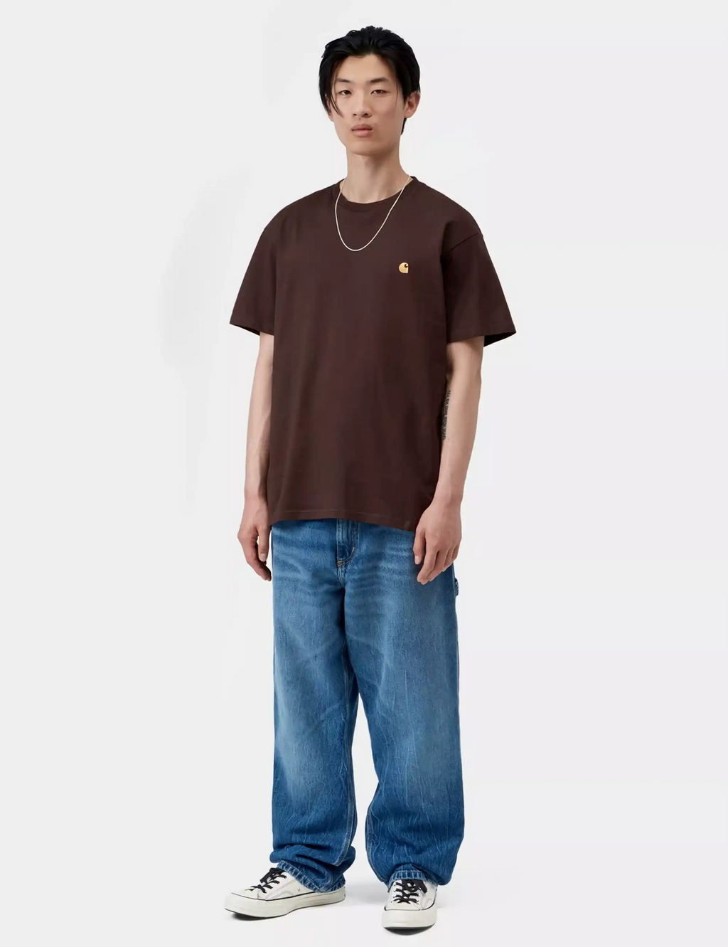 Chase T-shirt in dark brown with gold chest logo and crew neck, worn with blue jeans.