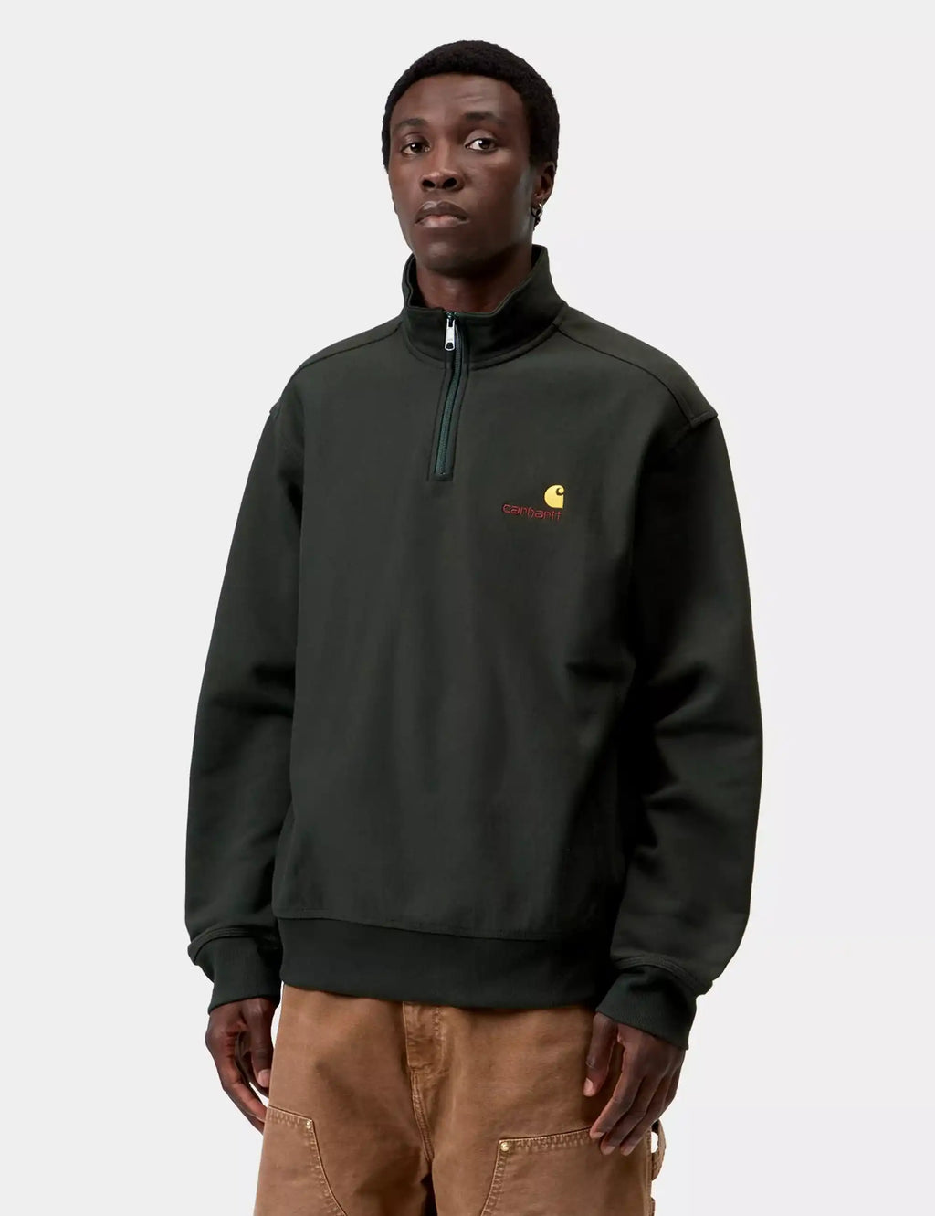 Carhartt WIP half-zip sweatshirt worn with pants, dark green, front chest logo