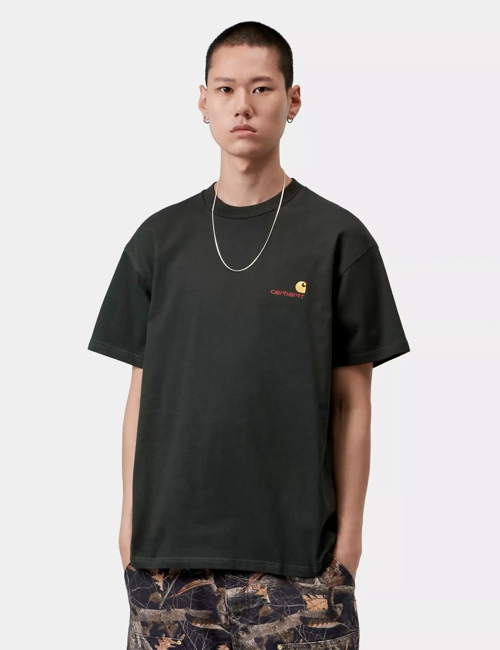Black crew-neck T-shirt with small chest script graphic; worn with patterned pants
