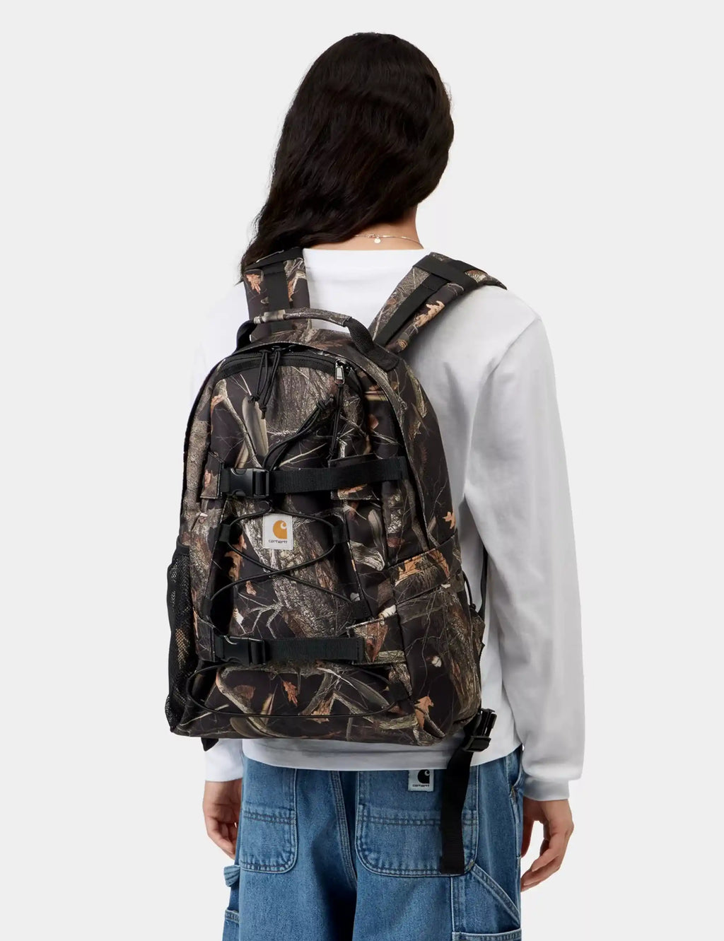 Camo backpack with black straps and top handle, worn on back view.